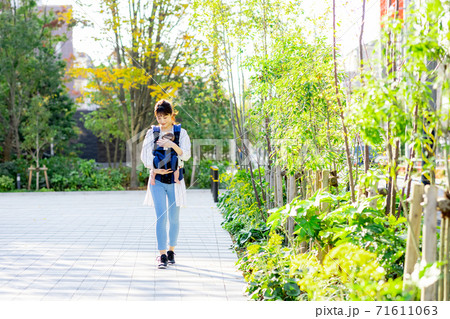 女性が抱っこ紐で赤ちゃんを連れて歩いている 女性が抱っこ紐で赤ちゃんを連れて歩いている 71611063
