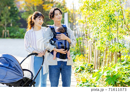 赤ちゃんを抱っこしながら外を歩く夫婦 71611073