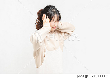 手で耳を塞ぐ若い女性 71611116