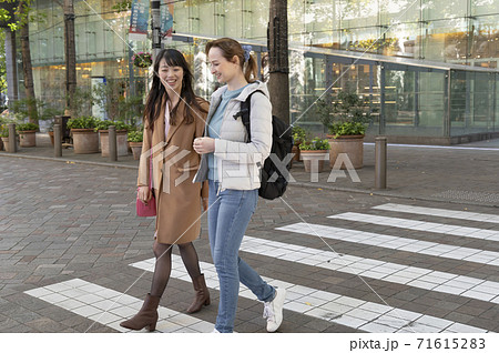 話しながら横断歩道を渡る日本人女性と外国人女性 話しながら横断歩道を渡る日本人女性と外国人女性 71615283
