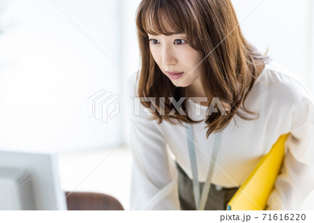 中腰でデスクトップモニターを覗き込むビジネスウーマン 71616220