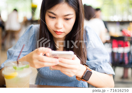 Beautiful asian women typing text on smartphone Beautiful asian women typing text on smartphone 71616250