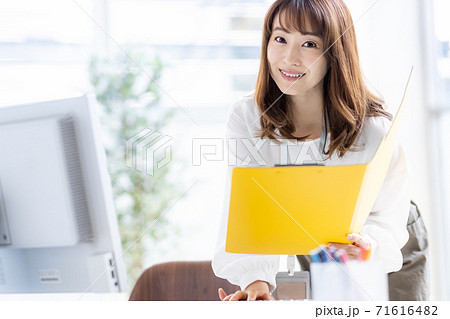 中腰でデスクワークをする多忙なビジネスウーマン(カメラ目線) 中腰でデスクワークをする多忙なビジネスウーマン(カメラ目線) 71616482