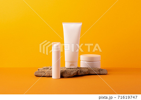 Group of cosmetic tubes bottles podium from natural materials orange background Group of cosmetic tubes bottles podium from natural materials orange background 71619747