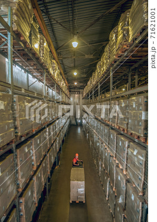 Warehouse worker going among the shelves in a warehouse 71621001