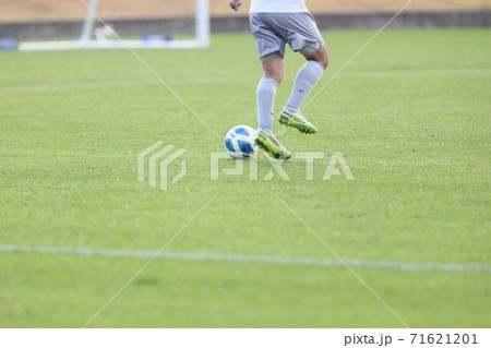 サッカー場で試合中にボール蹴ってるサッカー選手の腰から足先部分の写真素材