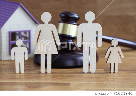 Wooden figurines of parents and children stand on table near toy house and judges hammer Wooden figurines of parents and children stand on table near toy house and judges hammer 71621340