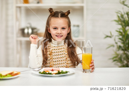 little child girl having breakfast - fried egg and orange juice 71621820