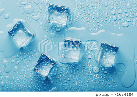 Ice cubes with drops of melt water water on a blue background, top view. Ice cubes with drops of melt water water on a blue background, top view. 71624184