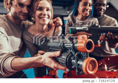 Group of young friends posing with guns in arcade. Group of young friends posing with guns in arcade. 71624720