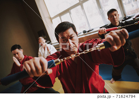 Male trainer shows nunchucks and looks at camera.  71624794