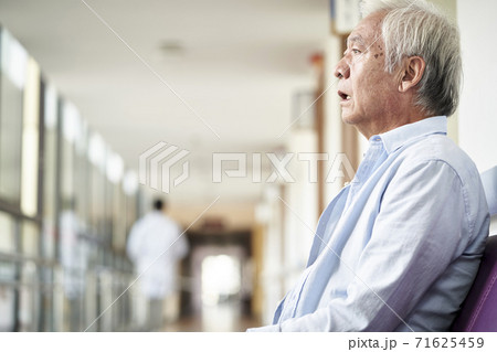 asian old man sitting in hospital hallway looking sad and depressed 71625459