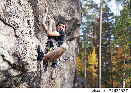 cute teen kid climbing on rock with insurance, lifestyle sport people concept 71625927
