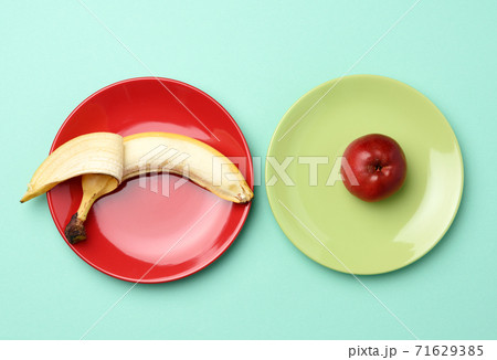 red ripe apple and banana lie in a round ceramic plate red ripe apple and banana lie in a round ceramic plate 71629385