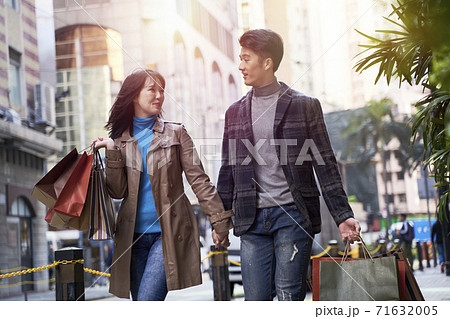 happy and loving young asian couple walking on street with shopping bags in hand 71632005