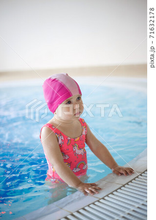 little girl in a pool cap and blue swimsuit learns to swim in the pool 71632178
