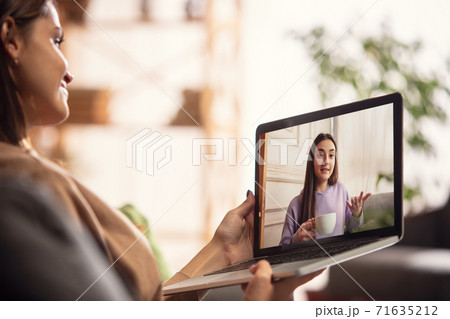 Celebration and holidays during quarantine concept. Friends or family unpacking gifts while talking using video call Celebration and holidays during quarantine concept. Friends or family unpacking gifts while talking using video call 71635212