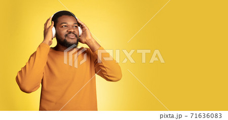 Young african-american man's portrait isolated on yellow studio background, facial expression. Beautiful male half-lenght portrait with copyspace. 71636083