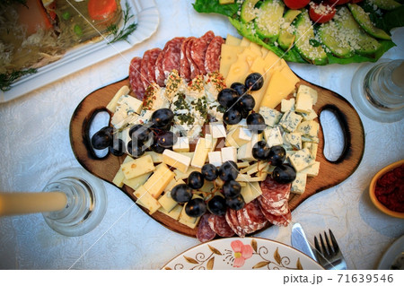 Cheese and meat platter on a wooden board on a festive table. View from above. 71639546