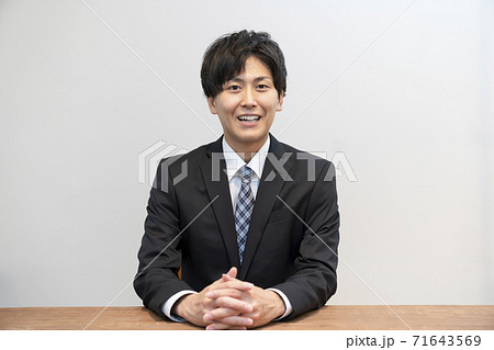 相手に向かって話をするスーツ姿の若い男性　 71643569
