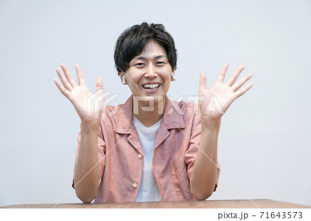カメラ目線で両手を振るワイヤレスヘッドホンをした若い男性 カメラ目線で両手を振るワイヤレスヘッドホンをした若い男性 71643573