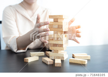 Businessmen carefully placed wooden blocks in a high tower, Protecting a tall wooden tower also involves a high risk, wooden blocks concept. Businessmen carefully placed wooden blocks in a high tower, Protecting a tall wooden tower also involves a high risk, wooden blocks concept. 71648105