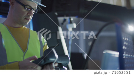 Focused service engineer programs industrial robot arm using teach pendant control Focused service engineer programs industrial robot arm using teach pendant control 71652551