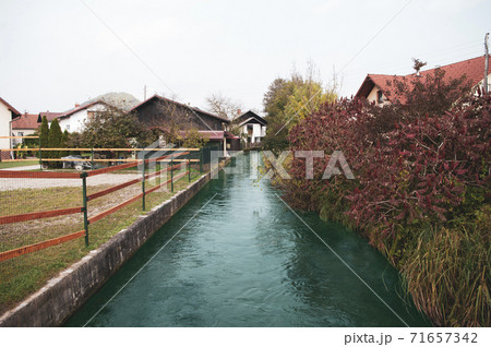 Small river goes in village between houses, autumn season. 71657342