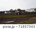 Red tractor plowing field in autumn season in the village 71657343