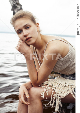 young blond woman hanging on birch tree at lake shore, summer vacations outdoor lifestyle young blond woman hanging on birch tree at lake shore, summer vacations outdoor lifestyle 71659407