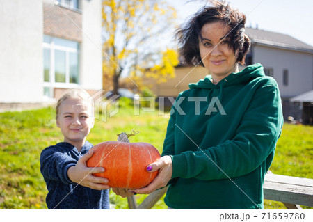 Mother and daughter show a pumpkin they grew at their farm 71659780