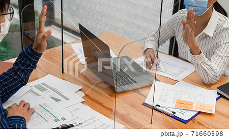 business team brainstorm they are working hard by looking through the plastic protective wall, concept of social distancing to prevent the spread of coronavirus COVID-19. 71660398