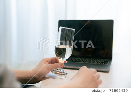 パソコンの前で飲み物を飲む。家でリモート・オンライン飲み、おうち時間。 パソコンの前で飲み物を飲む。家でリモート・オンライン飲み、おうち時間。 71662430