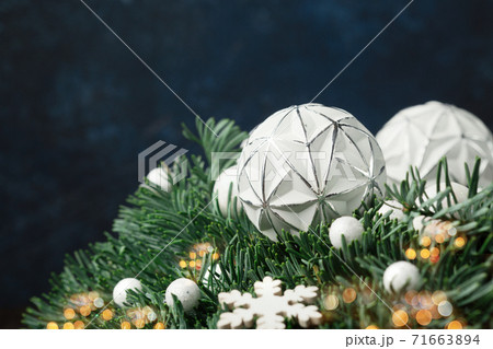 Christmas winter table setting with advent Xmas wreath, white candles, green branches and snowflakes on dark blue wooden background. 71663894