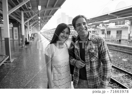 Persian tourist man and young Asian tourist woman together at the railway station 71663978
