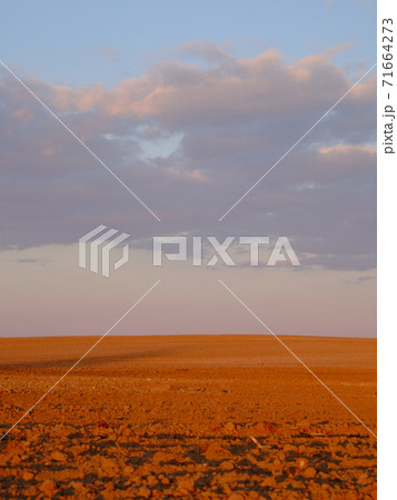 Cloudy evening sky over an empty agricultural field. Bright sunset landscape. 71664273