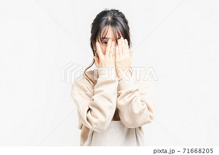 手で顔を隠す若い女性の写真素材