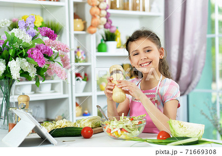 Portrait of cute little girl preparing fresh salad 71669308
