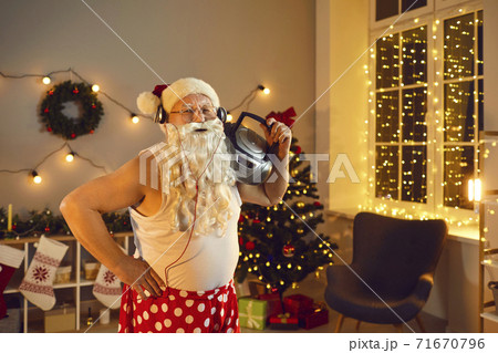 Funny granddad with Santa beard, headphones and boombox having fun on Christmas night at home 71670796