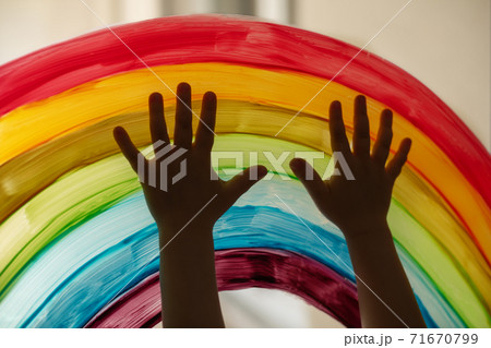 Child's hands touch painting rainbow on the window 71670799
