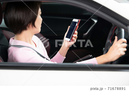 運転中にスマホ操作をする女性　 71678891