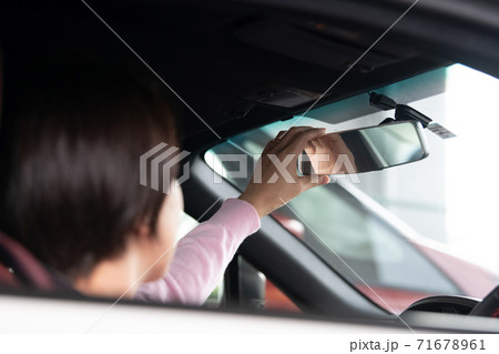 クルマを運転する女性 バックミラーの角度を直す女性の写真素材