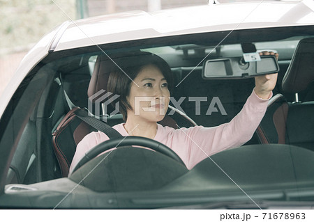 クルマを運転する女性・バックミラーの角度を直す女性 クルマを運転する女性・バックミラーの角度を直す女性 71678963