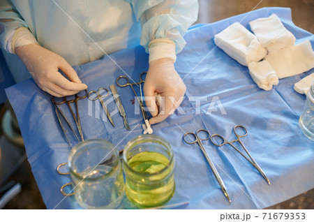 Surgery. On the table, the tools are arranged in a specific order. Gloved hands of the medic are visible. Surgery. On the table, the tools are arranged in a specific order. Gloved hands of the medic are visible. 71679353