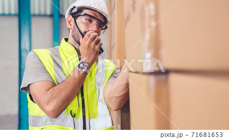 Professional cargo worker talks on portable radio to contact another worker 71681653