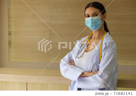A female doctor wearing a mask is standing at the reception. 71682141