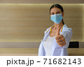 A female doctor wearing a medical mask raising his thumbs. 71682143