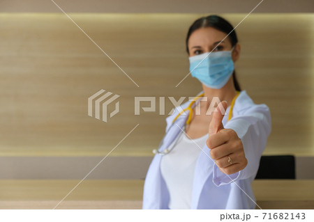 A female doctor wearing a medical mask raising his thumbs. A female doctor wearing a medical mask raising his thumbs. 71682143