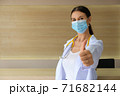 A female doctor wearing a medical mask raising his thumbs. 71682144