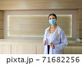 A female doctor wearing a mask is standing at the reception. 71682256